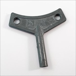 May include: A gray, Y-shaped key with two circular holes at the top and a rectangular emblem. The key has a textured surface and a cylindrical handle. The key is likely for a mechanical device.