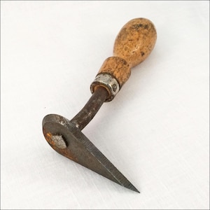 May include: A vintage woodworking tool with a wooden handle and a curved, metal blade. The handle is light brown, and the metal components show signs of age and use. The blade has a sharp, pointed end. This tool is likely used for shaping or carving wood.