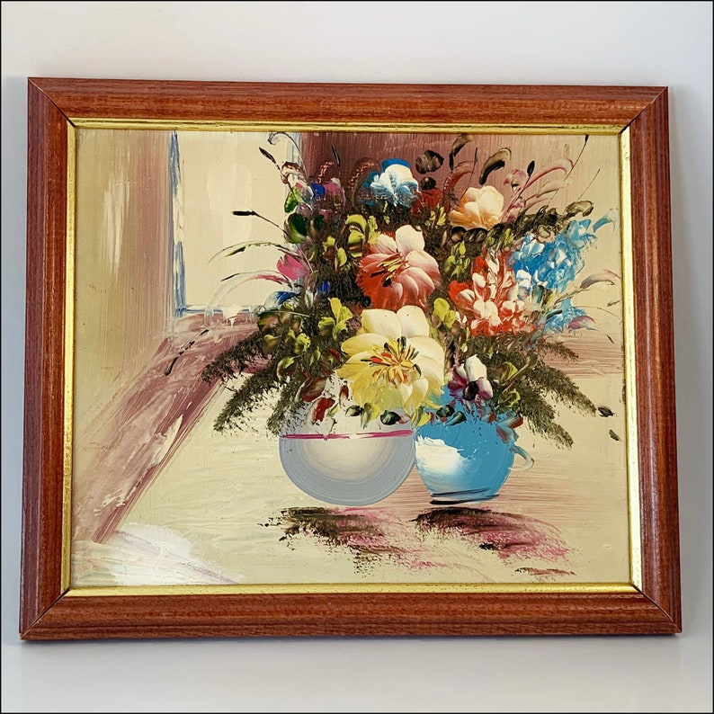 May include: A framed painting of a still life featuring a bouquet of colorful flowers in two ceramic vases. The flowers are in shades of pink, yellow, blue, and white. The vases are a light blue and a white with a pink stripe.