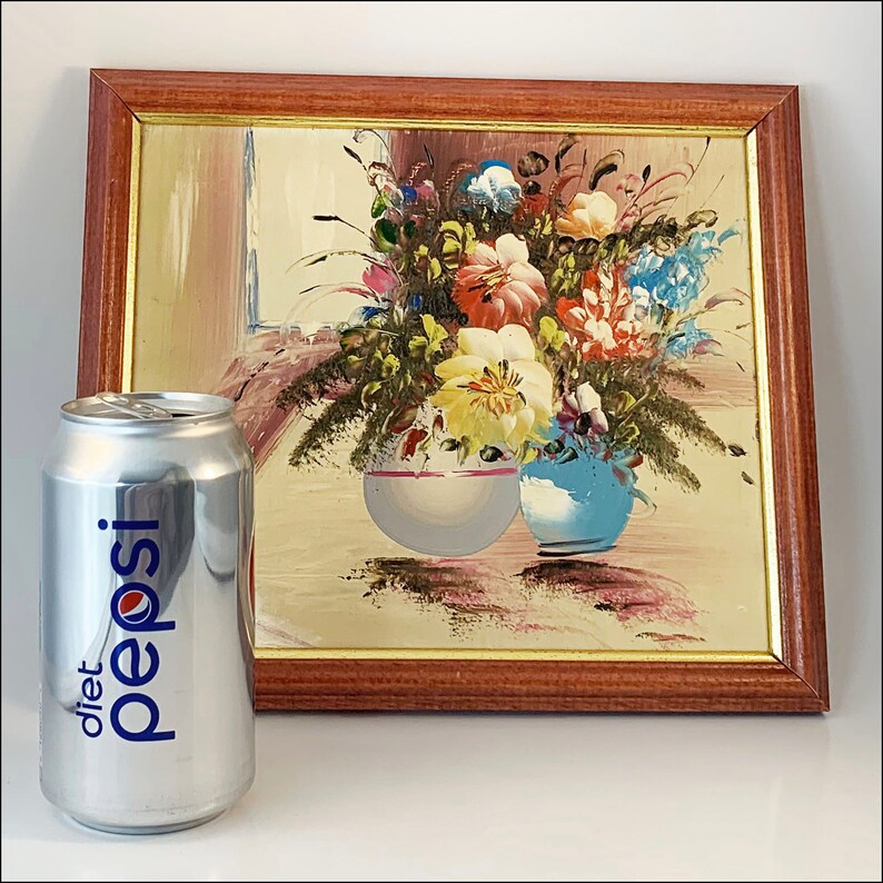 May include: A framed painting of a still life with a bouquet of colorful flowers in two vases. The vases are blue and white and the flowers are pink, yellow, red, and blue. The painting is in a wooden frame.