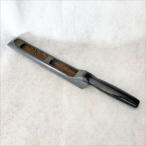 May include: A gray grater with a black handle. The grater has a rectangular shape with a textured grating surface and two rectangular openings. The handle is smooth and rounded, providing a comfortable grip for kitchen use.