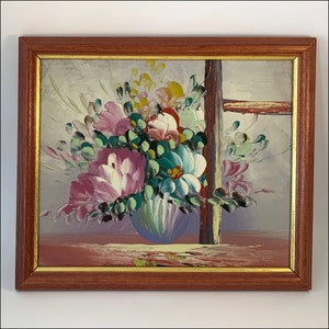 May include: A framed painting of a colorful floral arrangement in a blue vase. The flowers are pink, white, yellow, and green. The painting is set against a light gray background.