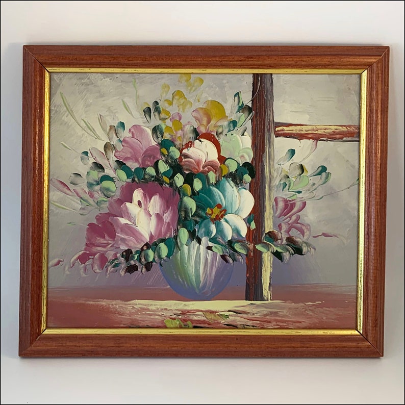 May include: A framed painting of a colorful floral arrangement in a blue vase. The flowers are pink, white, yellow, and green. The painting is set against a light gray background.