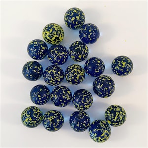 May include: A collection of seventeen spherical glass marbles, each featuring a deep navy blue base color with a dense, speckled pattern of bright neon yellow flecks distributed across the entire surface of every individual marble.
