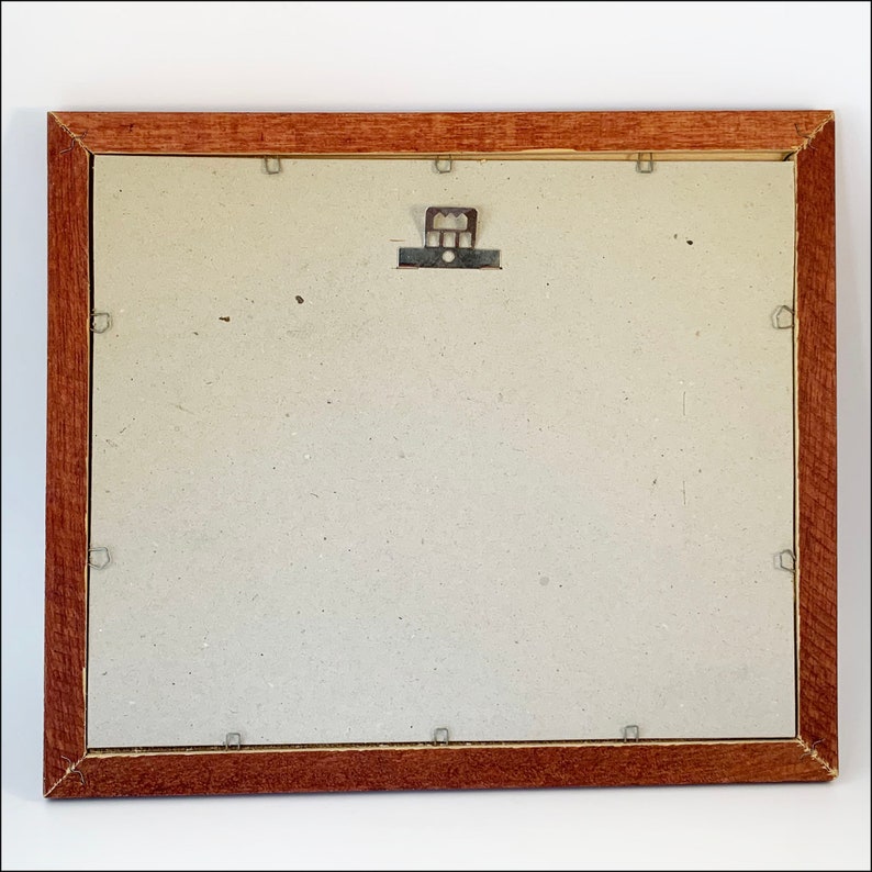 May include: The back of a brown wooden picture frame with a light gray mat and a metal hanging hook.