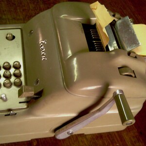 Puede incluir: Una m&aacute;quina de sumar vintage de color beige con un rollo de papel y una palanca en el lateral. La m&aacute;quina tiene un teclado num&eacute;rico y una ventana de visualizaci&oacute;n. El nombre de la marca "Facit" est&aacute; impreso en la m&aacute;quina.