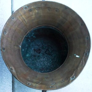 Puede incluir: Una olla de cobre vintage con una p&aacute;tina desgastada y un interior verde oscuro. La olla tiene un borde ancho y una base redonda.