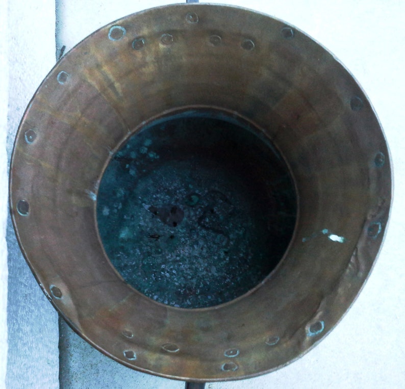 Puede incluir: Una olla de cobre vintage con una p&aacute;tina desgastada y un interior verde oscuro. La olla tiene un borde ancho y una base redonda.