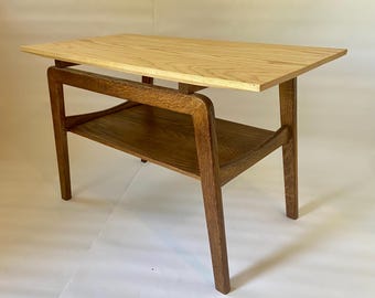 May include: A wooden side table with a light wood top and a darker wood lower shelf. The table has a simple, modern design with four legs.