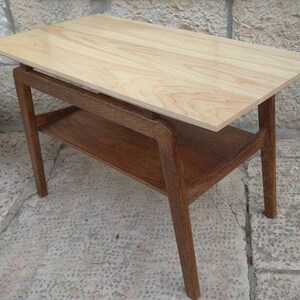 May include: A light wood end table with a lower shelf. The table has a simple, modern design with a rectangular top and four legs.