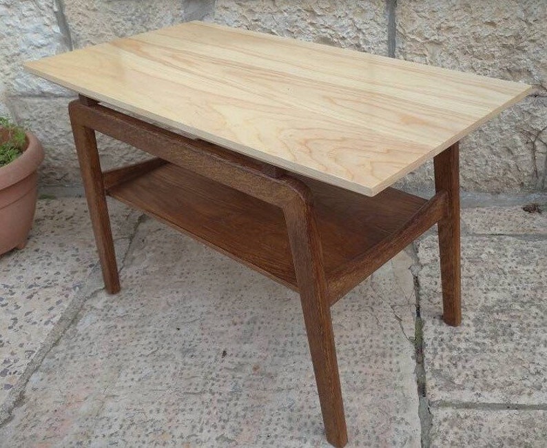 May include: A light wood end table with a lower shelf. The table has a simple, modern design with a rectangular top and four legs.