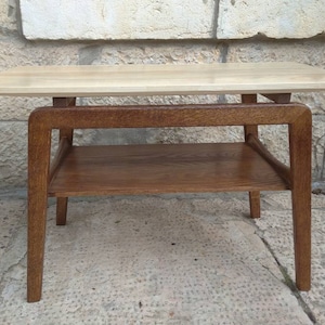 May include: A light wood end table with a lower shelf. The table has a simple, modern design with four legs and a rectangular top.