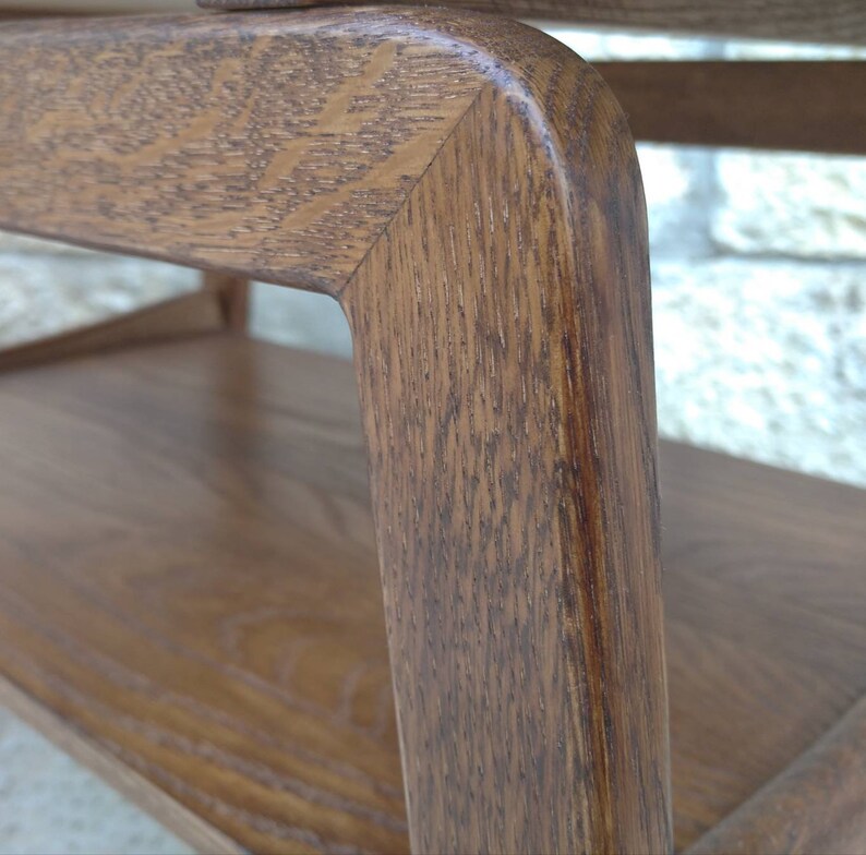 May include: Close-up of a wooden table with a rounded edge. The wood grain is visible and the table has a dark brown stain.