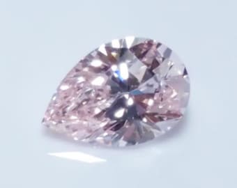 May include: A pear-shaped pink gemstone with a faceted cut. The gemstone is set against a white background.