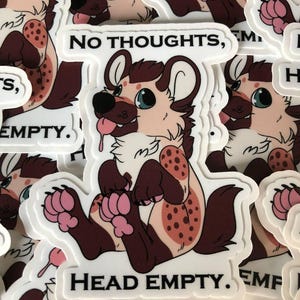 May include: A sticker featuring a cartoon hyena with brown and white fur and pink paws. The hyena is lying on its back with its tongue sticking out. The sticker has the text "NO THOUGHTS, HEAD EMPTY." printed on it.