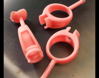 May include: Three pink plastic rings with a small handle on each. The rings are different sizes and shapes.