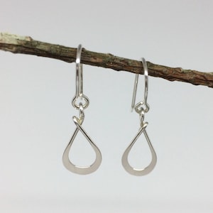 May include: A pair of silver teardrop shaped dangle earrings with a twisted wire design.