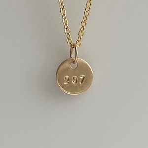 Peut inclure: Un collier en or avec un pendentif rond gravé du numéro 207.