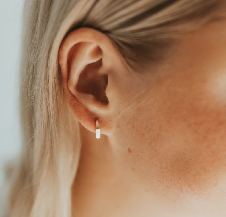 Puede incluir: Primer plano de una oreja con un peque&ntilde;o aro de oro.