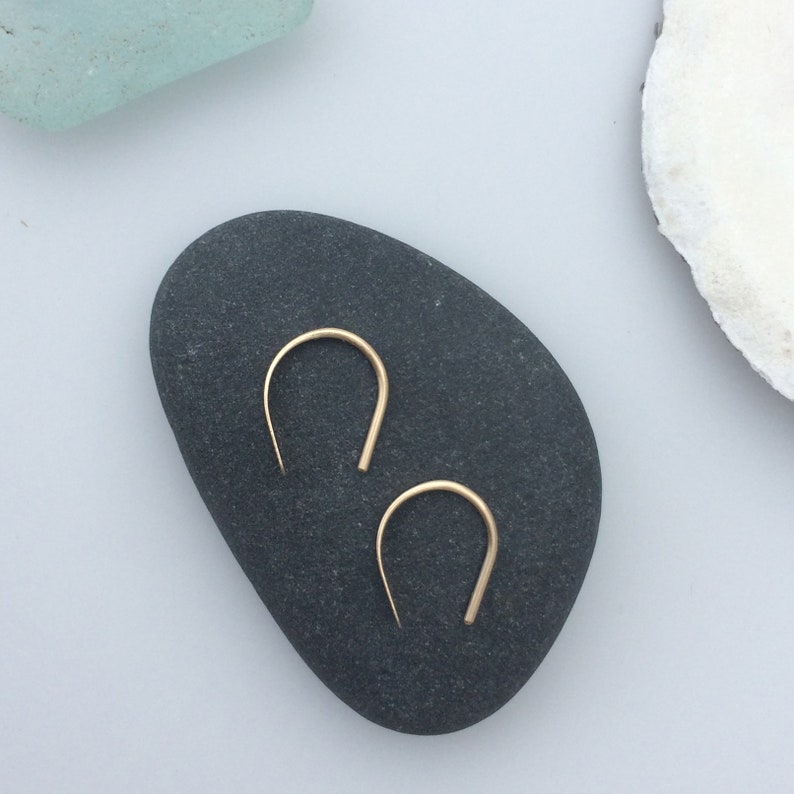 Puede incluir: Un par de pendientes de aro de oro con un dise&ntilde;o simple y minimalista. Los pendientes son peque&ntilde;os y delicados, y son perfectos para el uso diario.