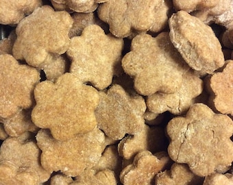 May include: A close-up of a large pile of homemade dog treats in the shape of stars. The treats are a light brown color and have a slightly rough texture.