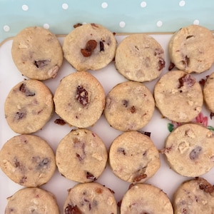 May include: A plate of homemade shortbread cookies with dried fruit and nuts. The cookies are round and have a light brown color. They are arranged in a circle on a white plate with a blue and white polka dot pattern.