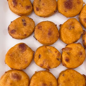 May include: A white plate with 13 golden brown fried food items. The food items are round and have a crispy texture.