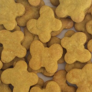 May include: A close-up of a pile of homemade dog treats in the shape of butterflies. The treats are a light brown color and have a slightly rough texture.