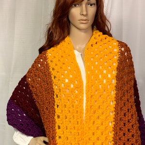 May include: A crocheted shawl with a striped pattern in shades of purple, brown, orange, and yellow.
