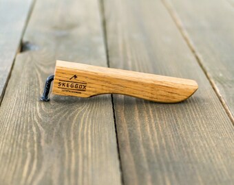 May include: A wooden bottle opener with a black metal pry bar. The opener is engraved with the text "SKEGGOX" and a small axe symbol.