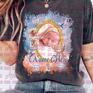 May include: Dark gray t-shirt with a memorial design. The design includes a baby's photo in a gold frame, doves, a teddy bear, and the text "In Loving Memory Of" and "Name Here".