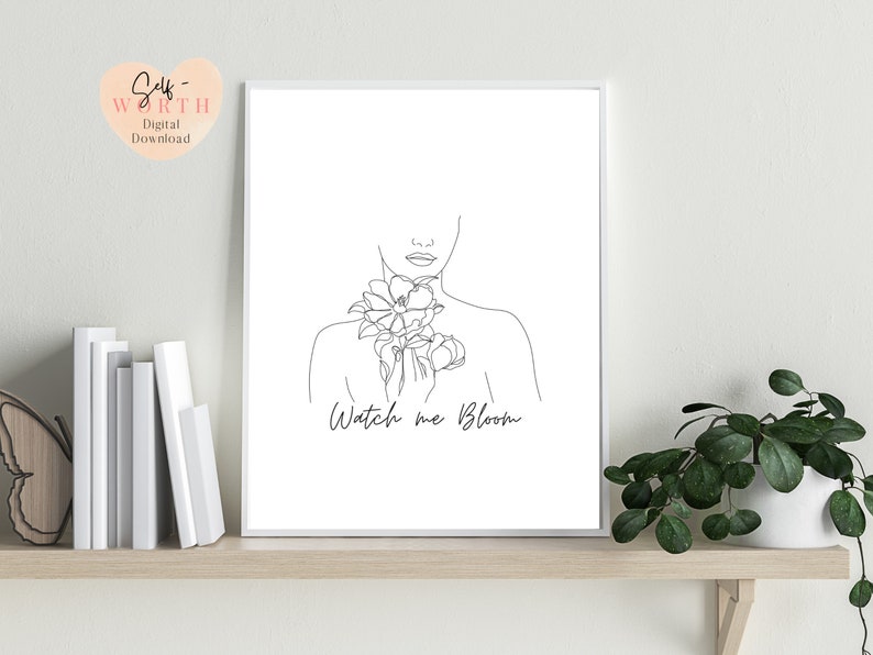 May include: Black and white line art print of a woman with flowers on her chest. The text "Watch me Bloom" is below the woman.
