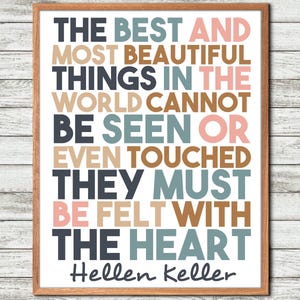 May include: A framed wall art print featuring the quote: THE BEST AND MOST BEAUTIFUL THINGS IN THE WORLD CANNOT BE SEEN OR EVEN TOUCHED THEY MUST BE FELT WITH THE HEART, attributed to Hellen Keller, in dark gray, blue, tan, and pink block lettering.