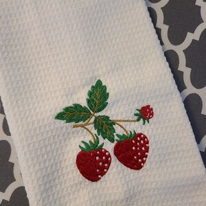 May include: White kitchen towel with embroidered red strawberries and green leaves.