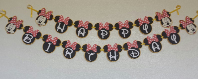 May include: A black and white banner with red polka dots and Minnie Mouse heads. The banner spells out "Happy Birthday".