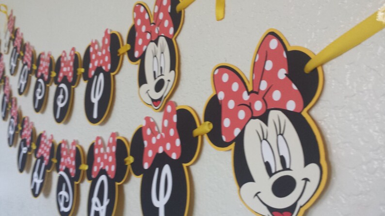 May include: A black and red Minnie Mouse themed banner with the word "Happy" in white letters. The banner is made of cardstock and has yellow string connecting the pieces.