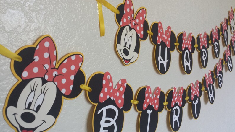 May include: A black and yellow Minnie Mouse themed banner with red polka dot bows and the words "Happy Birthday" in white.