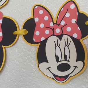 May include: A black and yellow Minnie Mouse banner with red polka dot bows. The banner has a yellow ribbon connecting the pieces.