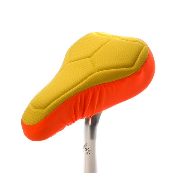 Housse de selle de vélo rembourrée orange pour enfants en textiles respectueux de l’environnement. Mousse de haute technologie pour un maximum de soutien et de confort et une base résistante à l’eau