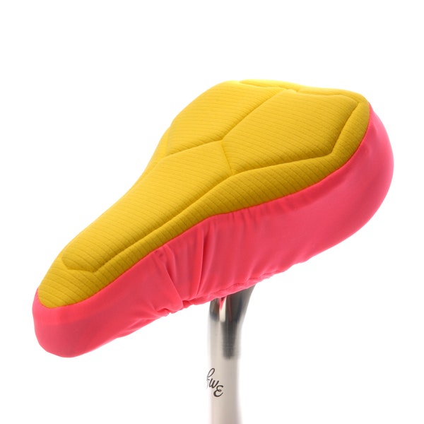 Housse de selle de vélo rembourrée rose pour enfants en textile respectueux de l'environnement. Mousse de haute technologie pour un soutien et un confort maximum et une base résistante à l'eau