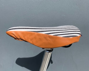 Humbug cognac, is a slim bicycle saddle cover lined with a splashproof base to keep you protected, comfortable and looking good!