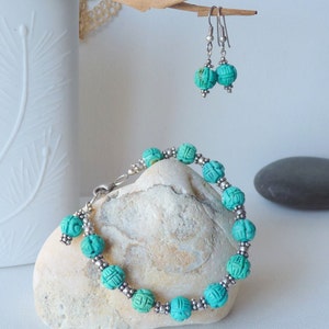 May include: A turquoise beaded bracelet and matching earrings. The bracelet features carved turquoise beads separated by small silver beads. The earrings have similar turquoise beads. The jewelry is displayed on a white surface.