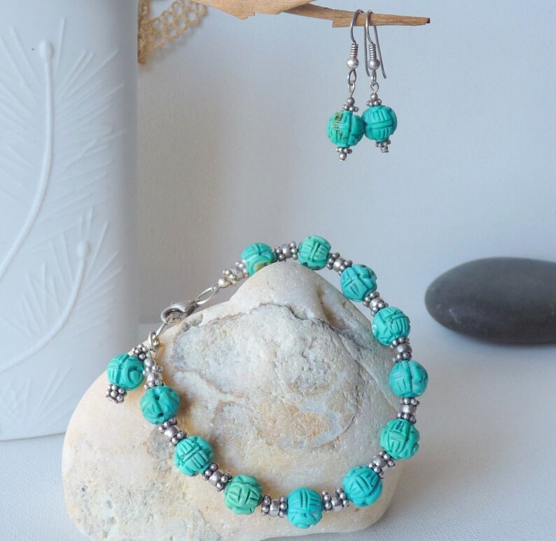 May include: A turquoise beaded bracelet and matching earrings. The bracelet features carved turquoise beads separated by small silver beads. The earrings have similar turquoise beads. The jewelry is displayed on a white surface.