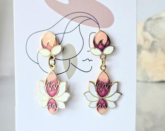 May include: A pair of gold-tone drop earrings featuring a lotus flower design with enamel detailing in shades of peach, magenta, and white. The earrings are displayed on a white card with a line drawing and the text Add exclusive elegance and beauty to women!