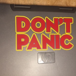 May include: A gray laptop with a red and yellow sticker that says "DON'T PANIC". The laptop has an HP logo on the bottom.