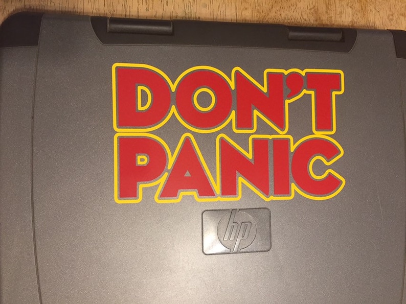 May include: A gray laptop with a red and yellow sticker that says "DON'T PANIC". The laptop has an HP logo on the bottom.