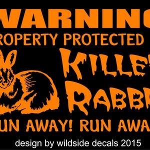 May include: Orange warning sign with black background. The sign reads "WARNING PROPERTY PROTECTED BY KILLER RABBIT RUN AWAY! RUN AWAY! design by wildside decals 2015". An orange silhouette of a rabbit is in the center of the sign.