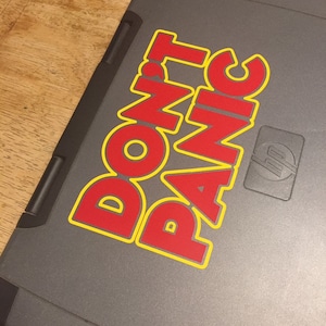 May include: A gray laptop with a red and yellow sticker that says "DON'T PANIC".