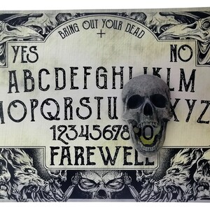 May include: A vintage-style Ouija board with a skull resting on the planchette. The board features the letters of the alphabet, numbers 1-9, and the words "Yes", "No", and "Farewell".