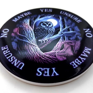 May include: A black and purple circular decision maker with an owl and a moon graphic. The words "YES", "MAYBE", "NO", "UNSURE" are written around the edge of the circle.